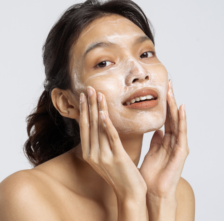 A girl scrubbing her face with cleanser. 