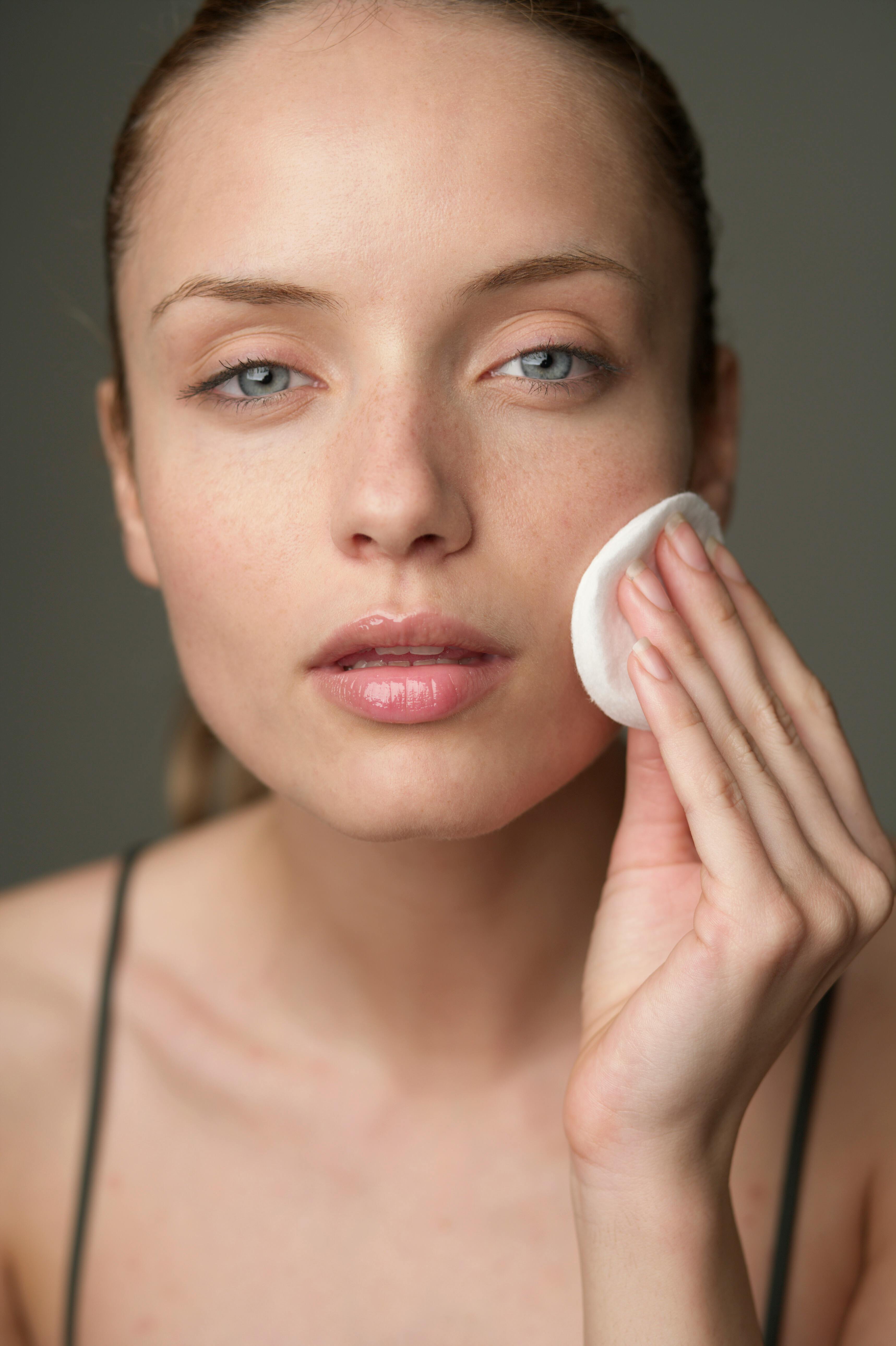 a girl dabbing her face with micellar water