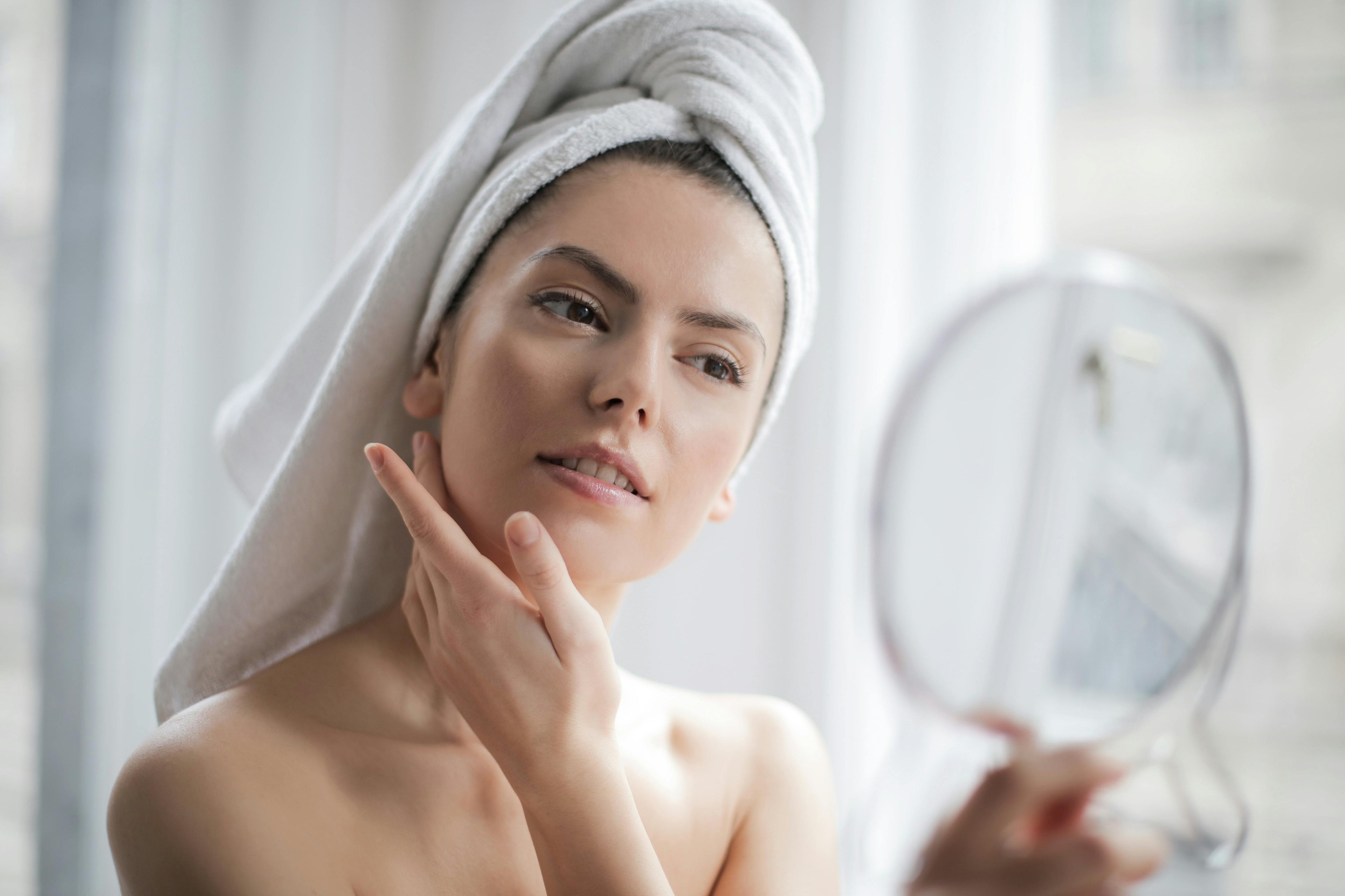 a girl with oily skin holding up a mirror and checking reflection