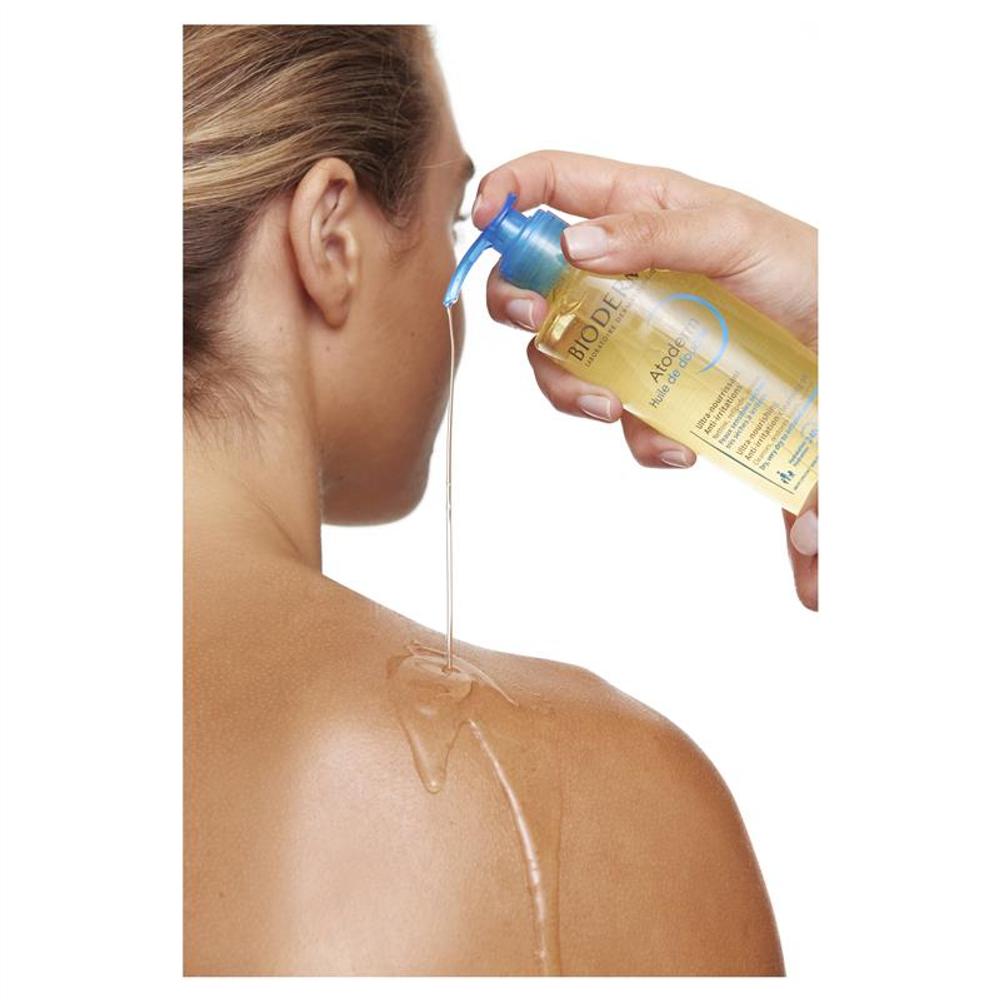 Person applying a clear oil from a bottle labeled 'Bioderma' to their shoulder.
